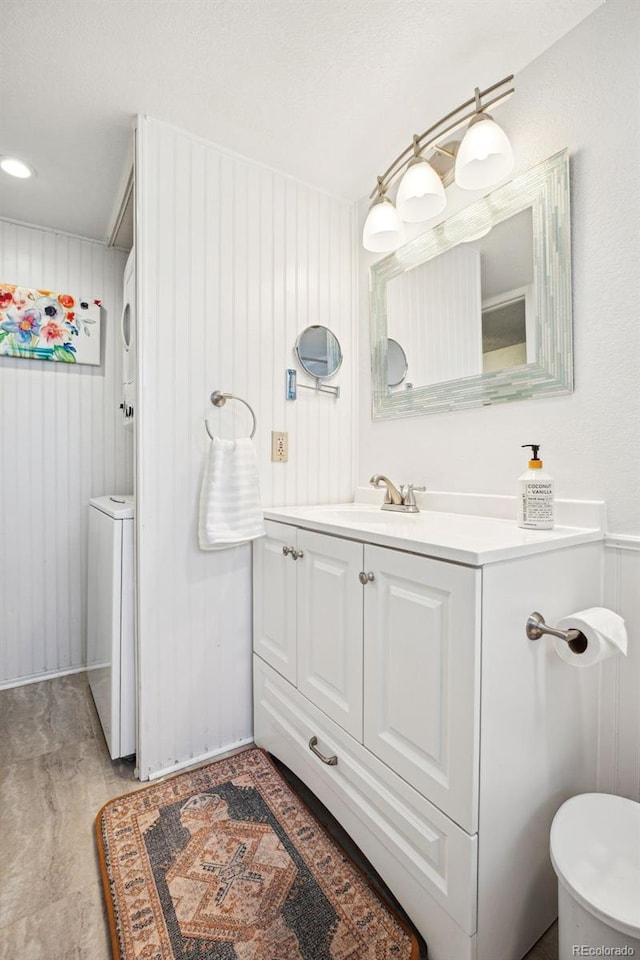 bathroom with washer / dryer, wooden walls, and vanity