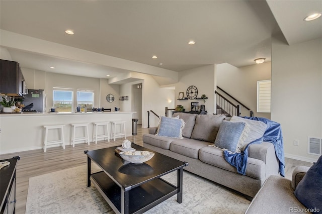 living area featuring visible vents, baseboards, recessed lighting, stairs, and light wood-style floors