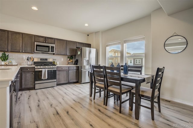 kitchen featuring dark brown cabinets, tasteful backsplash, appliances with stainless steel finishes, and light countertops