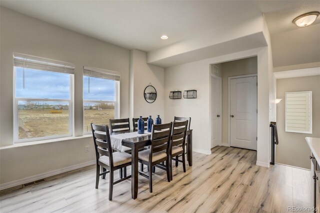 dining room featuring visible vents, baseboards, and light wood finished floors
