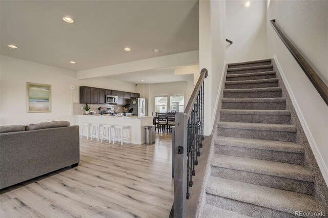stairway with recessed lighting, baseboards, and wood finished floors