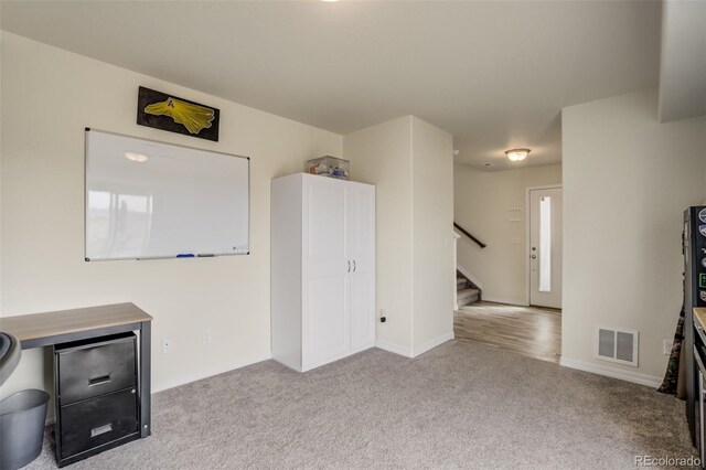 unfurnished living room with stairway, carpet, visible vents, and baseboards