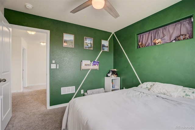 carpeted bedroom featuring visible vents, ceiling fan, baseboards, and a textured wall