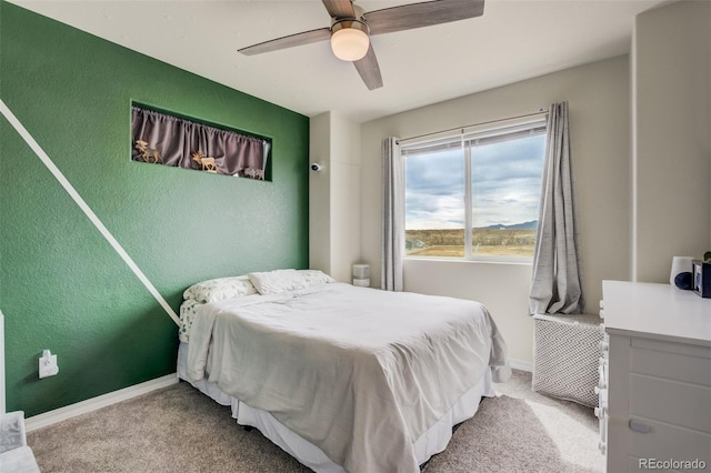 carpeted bedroom with a ceiling fan, baseboards, and a textured wall