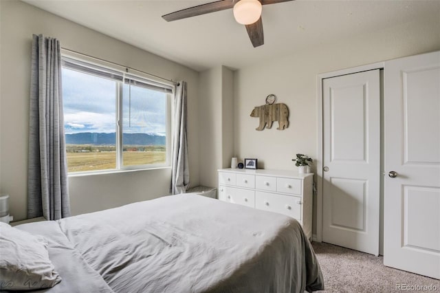 bedroom with a ceiling fan, light colored carpet, and a mountain view