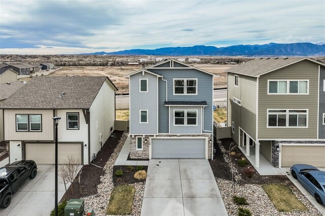 view of front of property featuring stone siding, a mountain view, an attached garage, and concrete driveway
