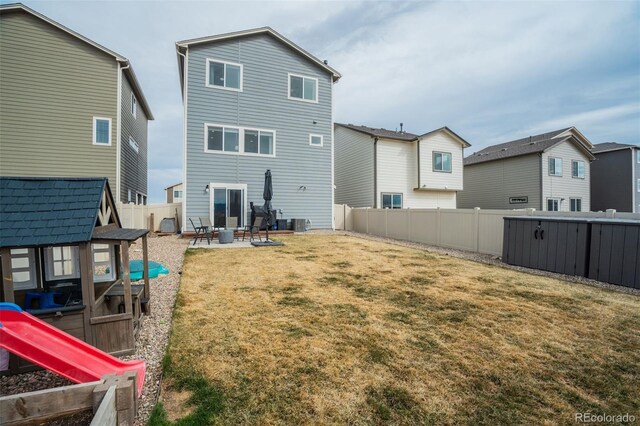 rear view of property with central air condition unit, an outbuilding, a lawn, a fenced backyard, and a patio area