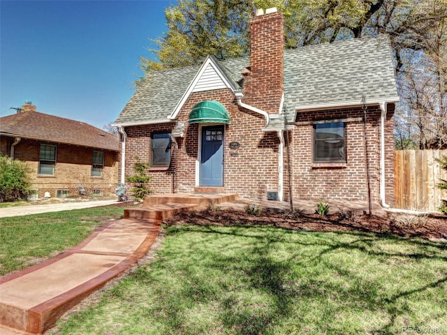 tudor-style house with a chimney, brick siding, and a shingled roof