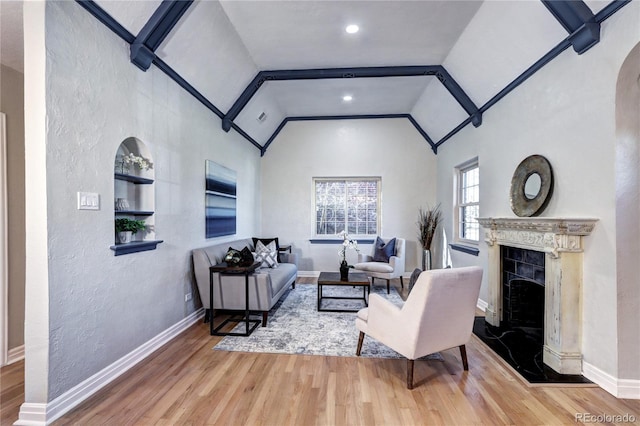 living room with lofted ceiling, wood finished floors, a premium fireplace, baseboards, and a textured wall