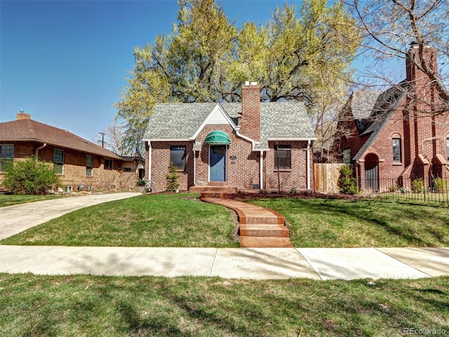 english style home with a chimney, brick siding, roof with shingles, and entry steps