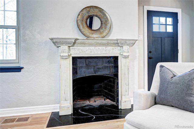 detailed view of wood finished floors, baseboards, a tiled fireplace, and a textured wall