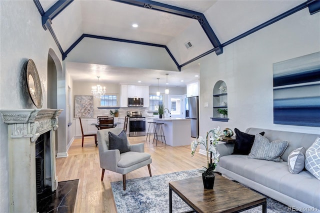 living area featuring light wood-style floors, a chandelier, baseboards, a fireplace with flush hearth, and high vaulted ceiling