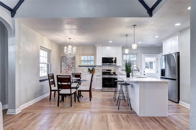 kitchen featuring appliances with stainless steel finishes, a sink, light countertops, baseboards, and white cabinets