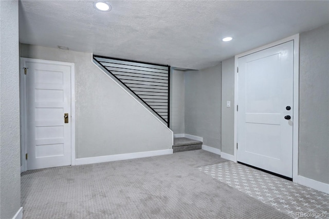 finished basement featuring baseboards, a textured ceiling, carpet floors, recessed lighting, and stairway