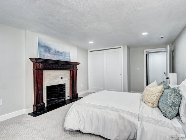 carpeted bedroom with baseboards, a closet, a fireplace, recessed lighting, and a textured ceiling