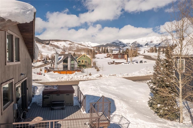 snow covered pool featuring a mountain view and a hot tub