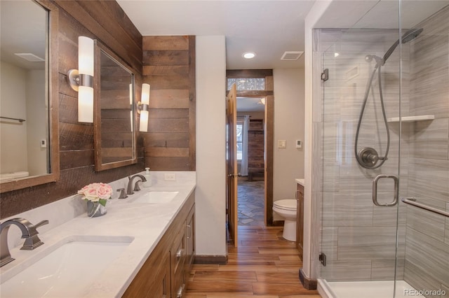 bathroom featuring vanity, hardwood / wood-style flooring, toilet, and a shower with shower door