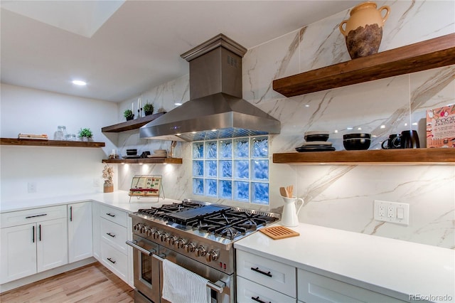 kitchen featuring tasteful backsplash, extractor fan, light hardwood / wood-style floors, white cabinetry, and range with two ovens