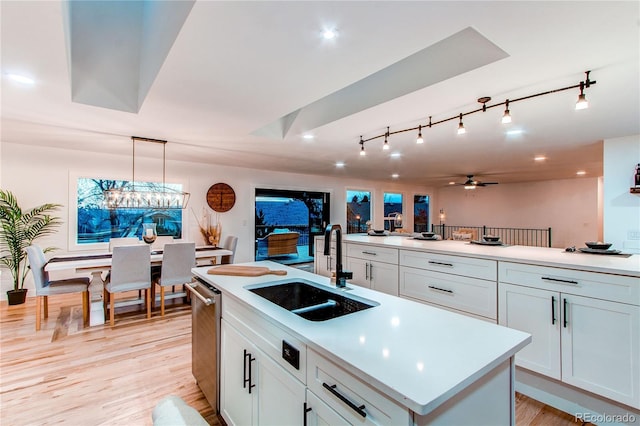 kitchen with ceiling fan, a kitchen island, pendant lighting, white cabinets, and sink