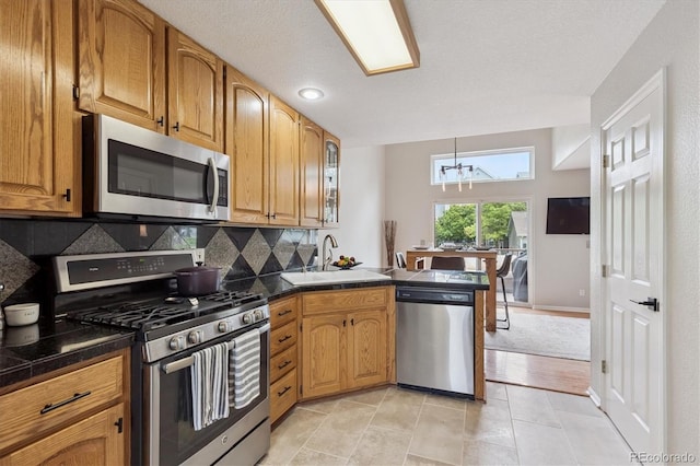943 Reynolds Farm Ln Unit D8, Longmont, CO 80503 - kitchen with appliances with stainless steel finishes, a peninsula, dark countertops, backsplash, and a chandelier