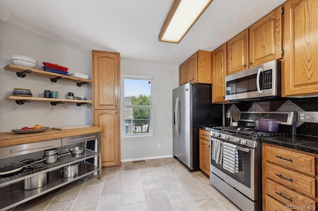 943 Reynolds Farm Ln Unit D8, Longmont, CO 80503 - kitchen with appliances with stainless steel finishes, tasteful backsplash, dark countertops, brown cabinetry, and open shelves