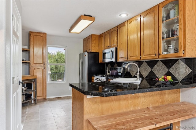 943 Reynolds Farm Ln Unit D8, Longmont, CO 80503 - kitchen with stainless steel appliances, backsplash, glass insert cabinets, a peninsula, and brown cabinets