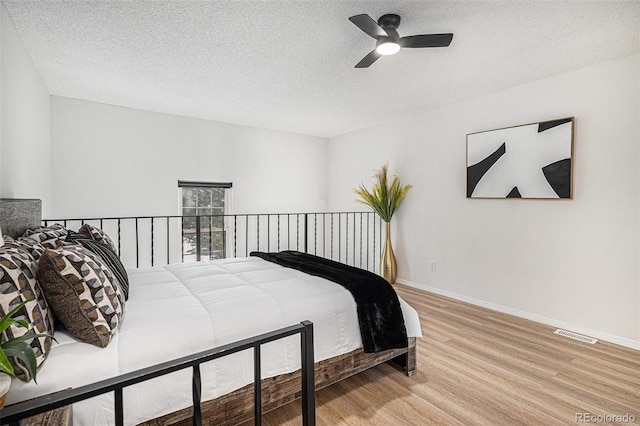 bedroom featuring baseboards, visible vents, a textured ceiling, and light wood-style floors