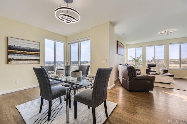 dining area with baseboards, a chandelier, and wood finished floors