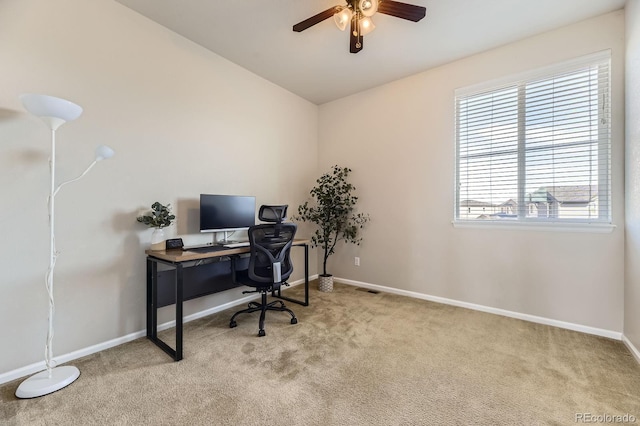 carpeted office space with ceiling fan, healthy amount of natural light, and baseboards
