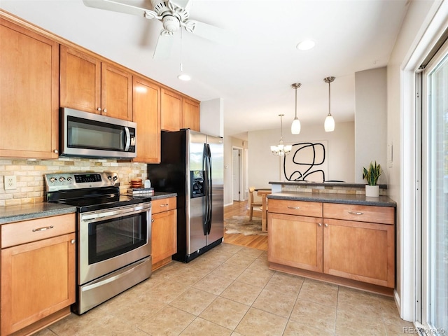 kitchen with pendant lighting, appliances with stainless steel finishes, light tile patterned flooring, and backsplash