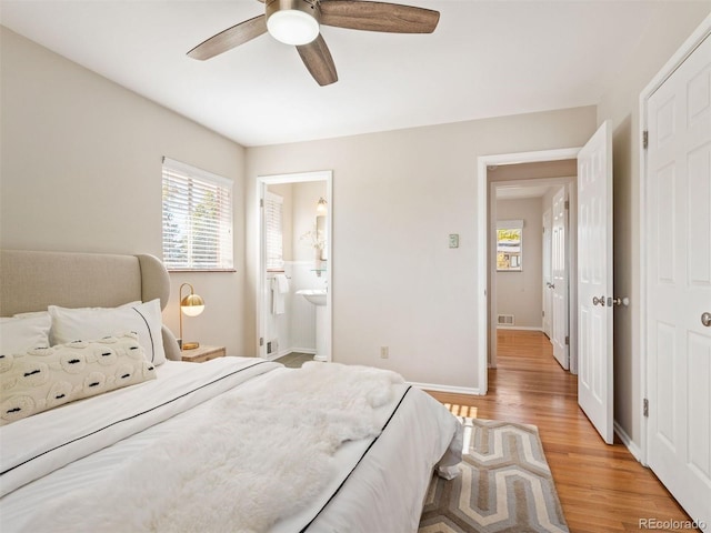 bedroom featuring ceiling fan, ensuite bath, and light hardwood / wood-style floors