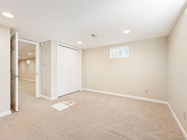 unfurnished bedroom with light colored carpet and a closet