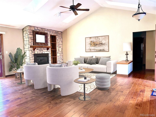 living room featuring ceiling fan, dark hardwood / wood-style flooring, a stone fireplace, and vaulted ceiling