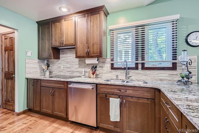 kitchen featuring light hardwood / wood-style floors, light stone countertops, black electric cooktop, sink, and stainless steel dishwasher