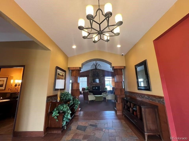 foyer entrance with recessed lighting, lofted ceiling, stone finish flooring, a chandelier, and a large fireplace