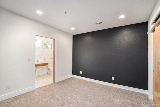 unfurnished bedroom featuring connected bathroom, a closet, and light colored carpet