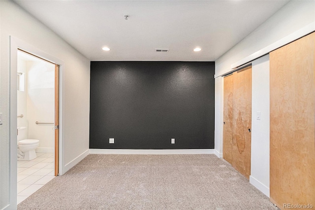 unfurnished bedroom with light carpet and ensuite bathroom