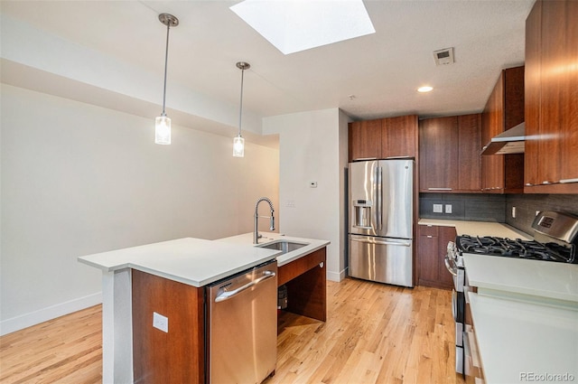 kitchen featuring sink, an island with sink, light hardwood / wood-style flooring, stainless steel appliances, and a skylight