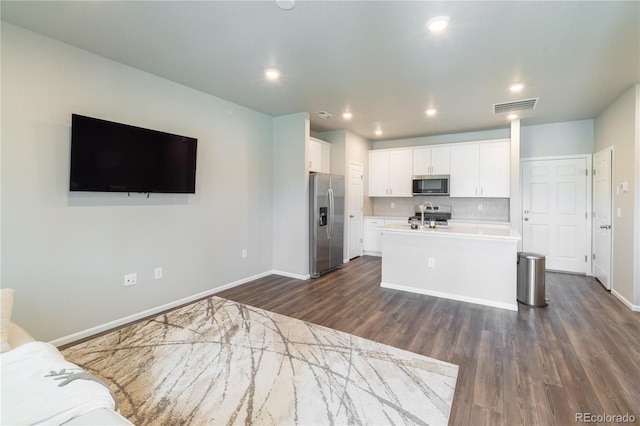 12213 Race St, Northglenn, CO 80241 - kitchen featuring appliances with stainless steel finishes, a kitchen island with sink, dark wood-style flooring, white cabinets, and light countertops