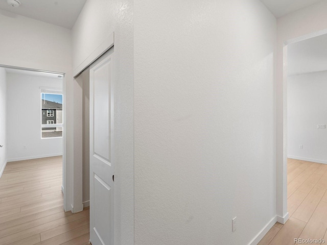 hallway featuring baseboards and light wood finished floors