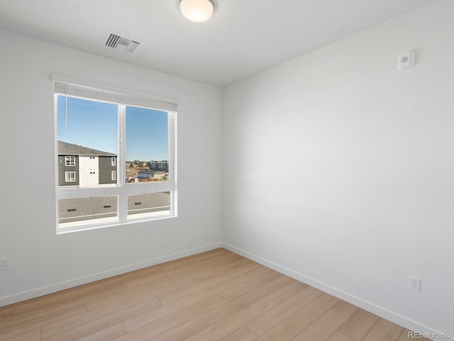 unfurnished room featuring light wood-type flooring, visible vents, and baseboards