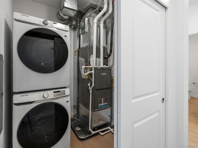 laundry room with stacked washer and dryer, laundry area, and wood finished floors