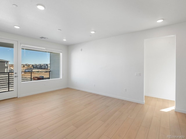 empty room featuring light wood-type flooring, visible vents, baseboards, and recessed lighting