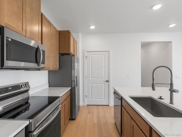 kitchen with light countertops, appliances with stainless steel finishes, brown cabinetry, and a sink