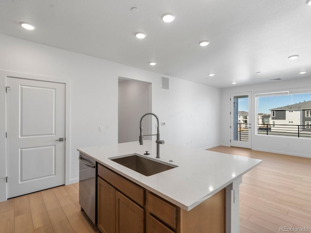 kitchen featuring a sink, visible vents, brown cabinets, dishwasher, and a center island with sink