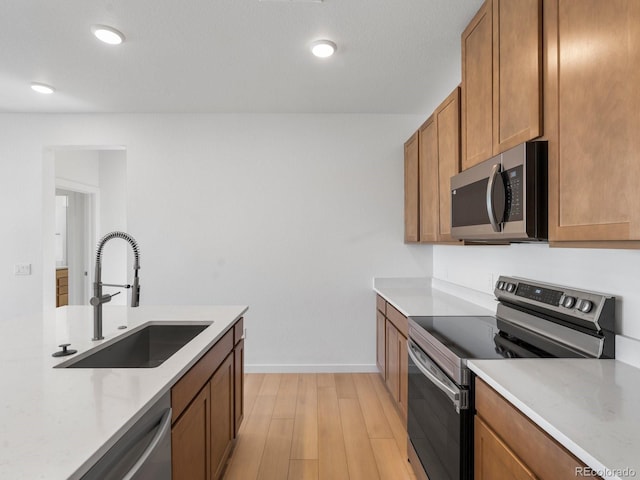 kitchen with stainless steel appliances, a sink, and brown cabinets