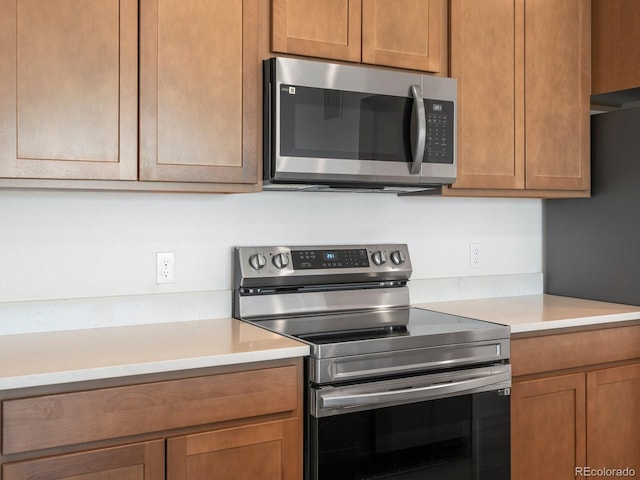 kitchen featuring brown cabinetry, appliances with stainless steel finishes, and light countertops