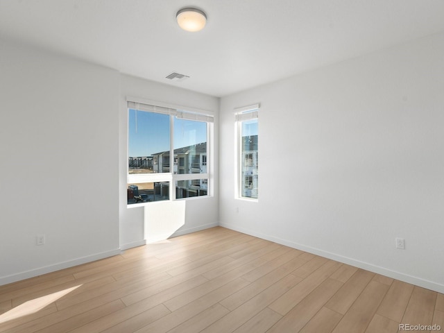 empty room with baseboards, visible vents, and light wood-style floors