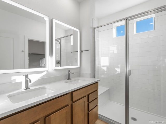 bathroom with double vanity, a stall shower, and a sink