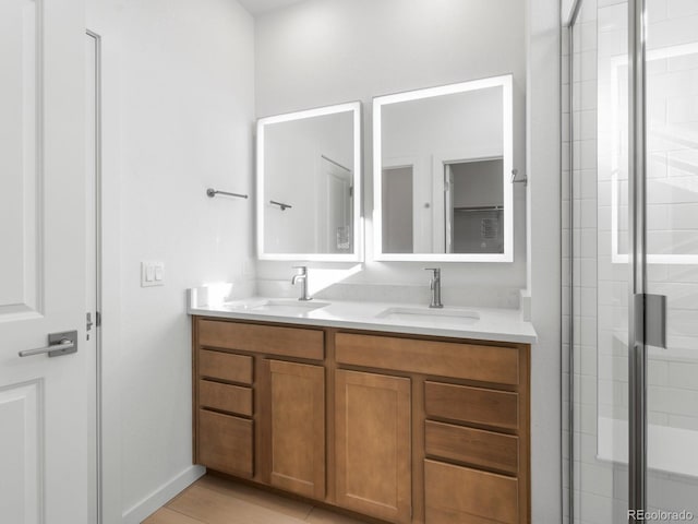 full bath with a sink, a shower stall, and double vanity